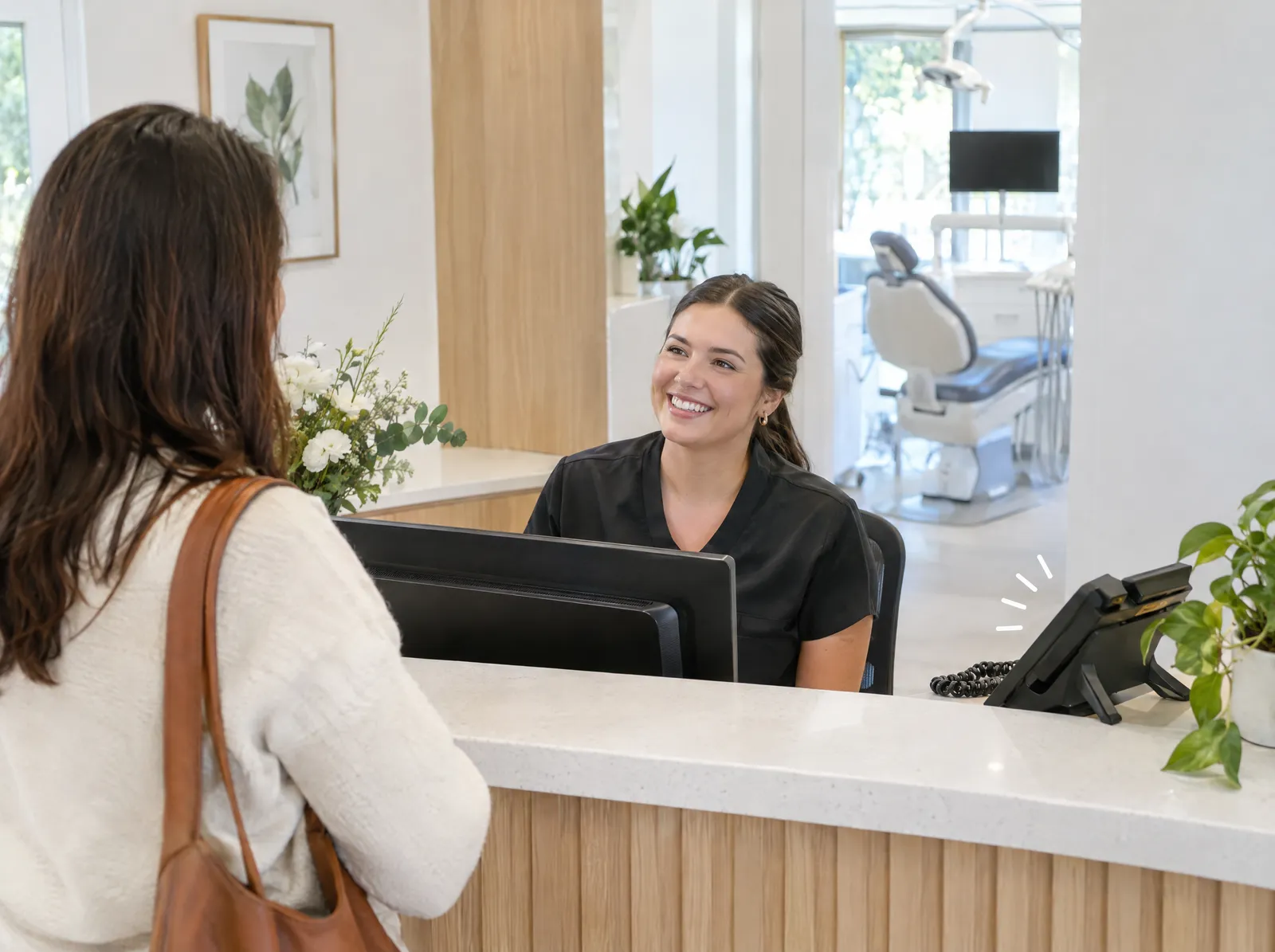 A dental receptionist greeting a patient at the front desk