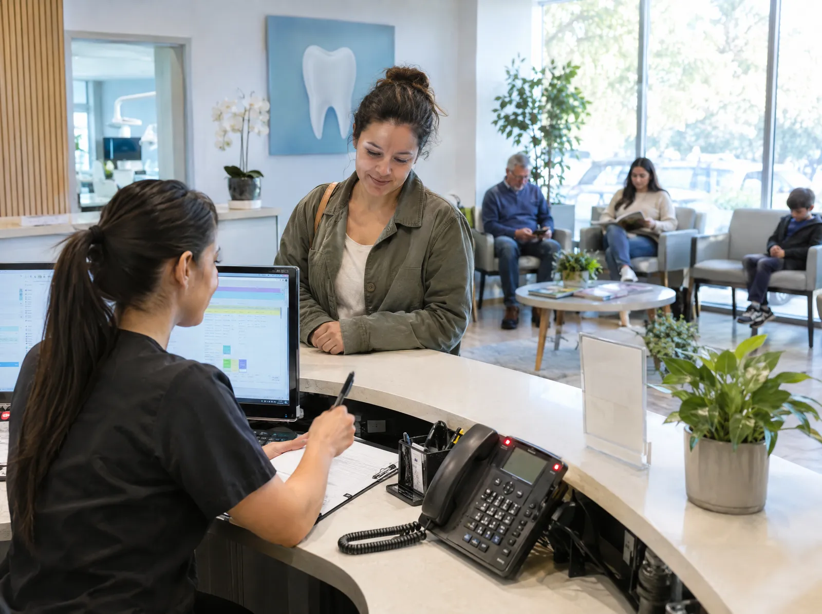A busy dental front desk with patients waiting while the phone rings